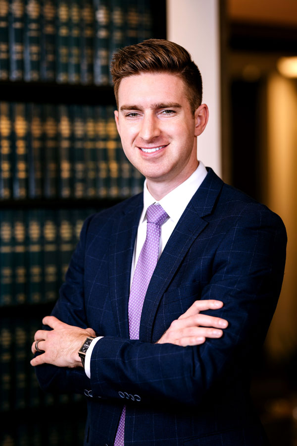 Attorney Connor J. Traut, in front of book shelves containing legal books.
